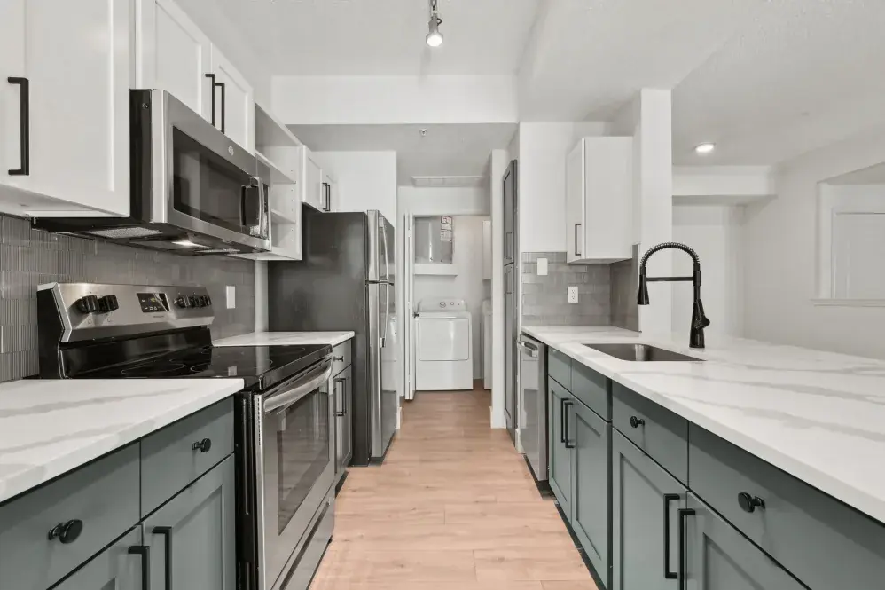 Finished galley kitchen with white counters, two-tone cabinetry, and black fixtures